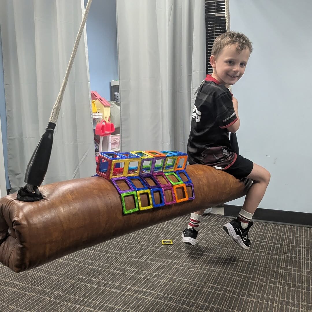 A child working on balance on a bolster swing in the clinic.
