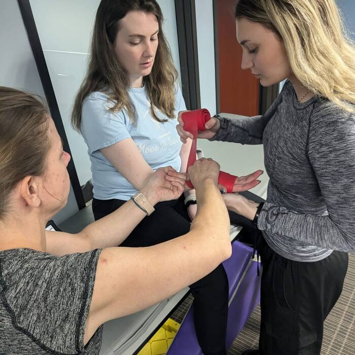 Hands-on manual therapy work using a resistance band during a treatment session.